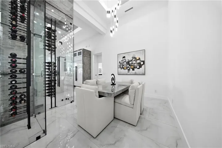 Dining room featuring wine glass display, chandelier, high ceiling