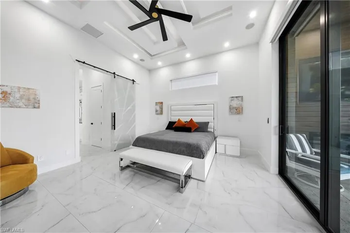 Master Bedroom with access to exterior, a barn door, ceiling fan, recessed lighting, and ensuite bath