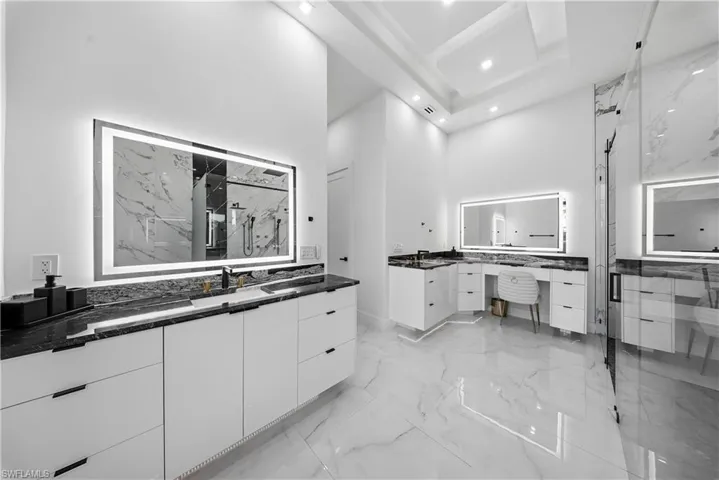 Full master bath featuring two vanities, a marble finish shower, a high ceiling, recessed lighting,