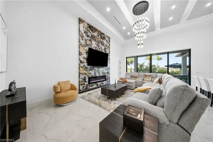 Living room with marble tiled flooring, a high ceiling, a fireplace, and hanging lights