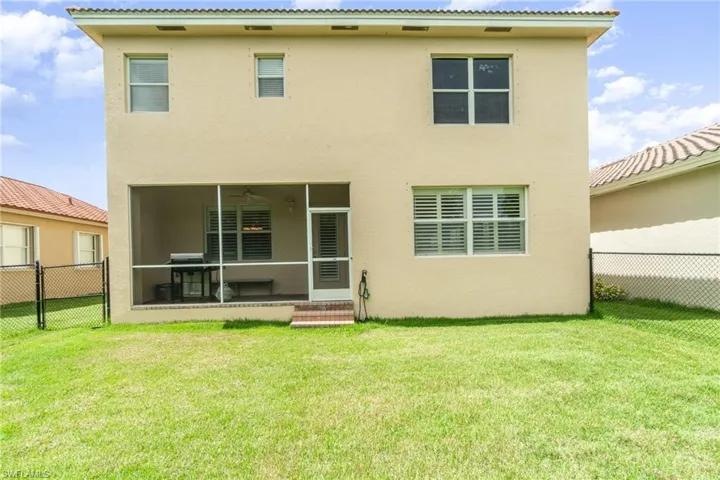 Rear view of house with a sunroom and a lawn