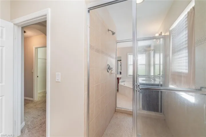 Bathroom 2 looking into Bathroom 1 separated by shower which can be entered through either side.  Both bathrooms have their own sink and toilet and one has a vanity and soaking tub.