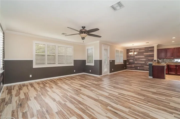 Unfurnished living room with ceiling fan with notable chandelier, a healthy amount of sunlight, light hardwood / wood-style flooring, and sink