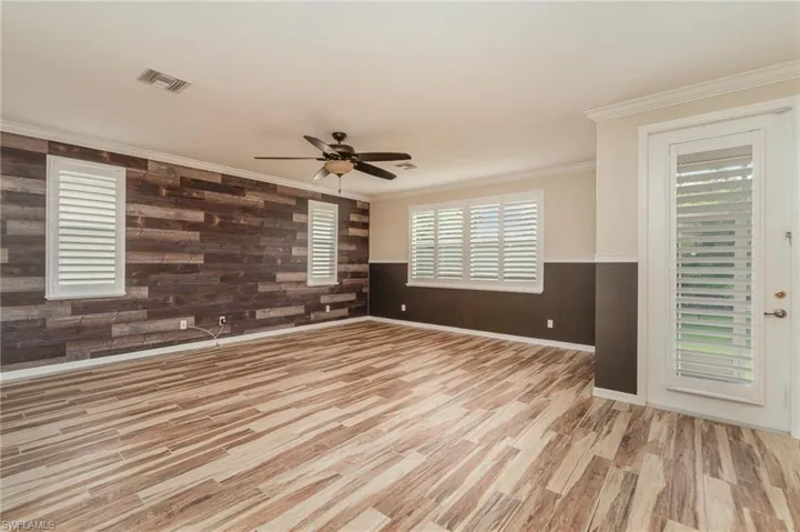 Spare room featuring ceiling fan, wood walls, light hardwood / wood-style flooring, and ornamental molding