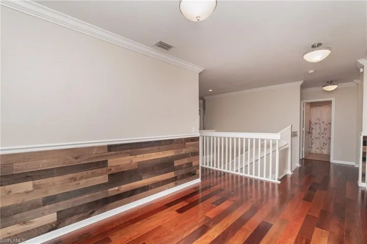 Hallway with hardwood / wood-style floors and ornamental molding