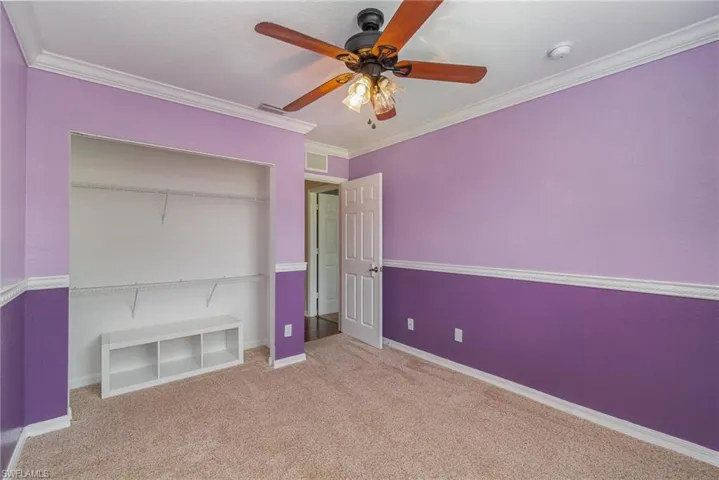 Unfurnished bedroom with ornamental molding, light carpet, a closet, and ceiling fan