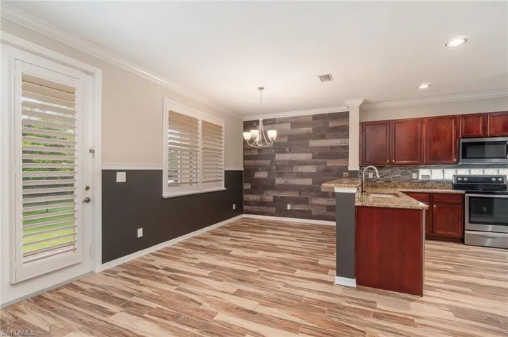Kitchen featuring appliances with stainless steel finishes, sink, pendant lighting, light stone countertops, and a notable chandelier