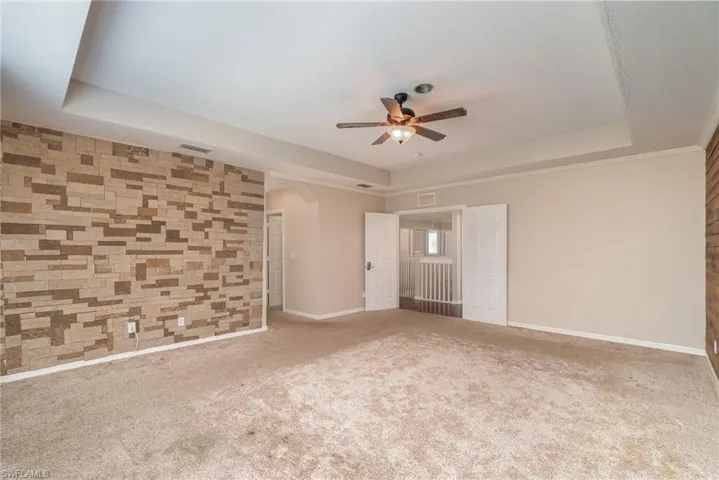 Unfurnished room featuring carpet floors, ceiling fan, and a raised ceiling