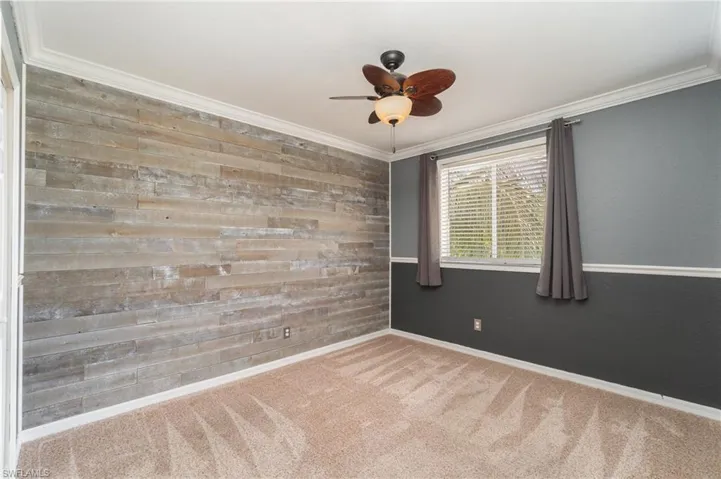 Spare room featuring carpet floors, ceiling fan, and ornamental molding