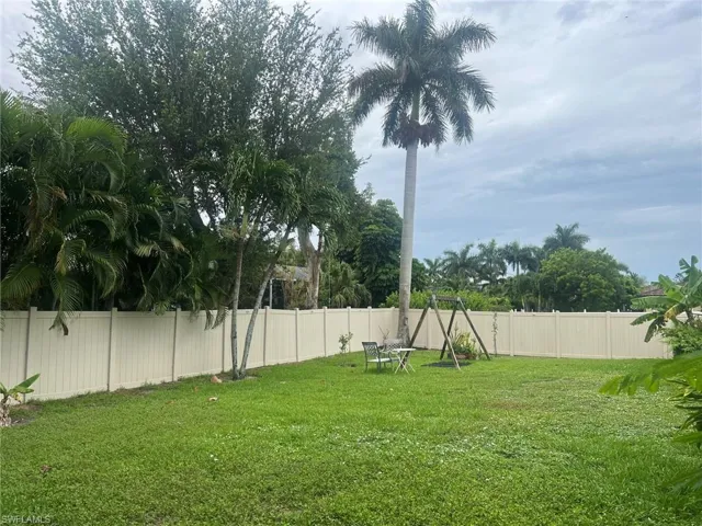 Expansive green lawn with mature palm trees and tropical foliage