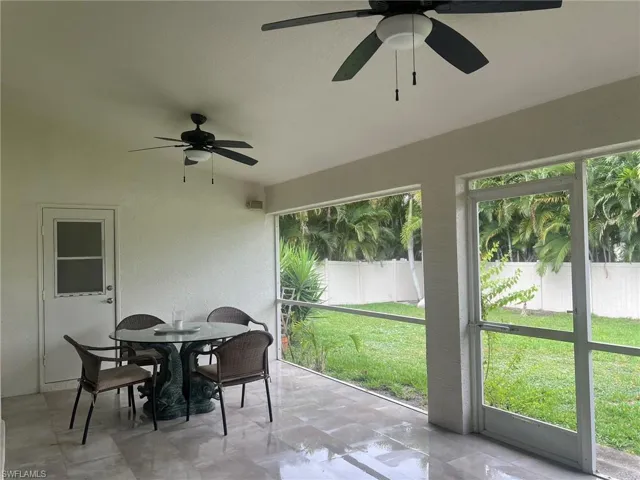 Expansive screened patio featuring two ceiling fans, a white exterior door with a window, a screened door to the yard, and tile flooring