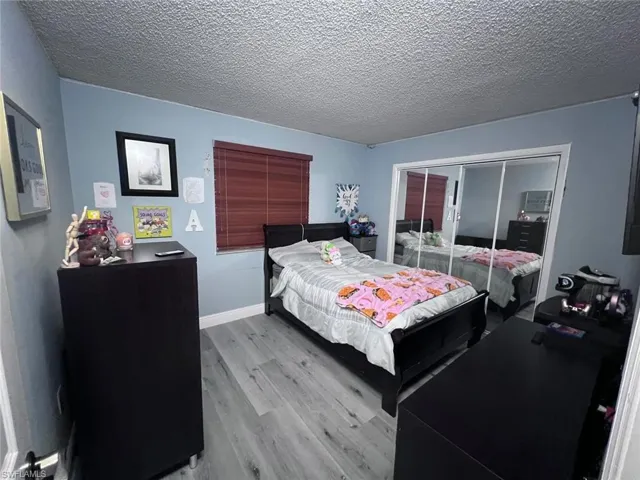 Bedroom with wood finished floors, a closet, and a textured ceiling