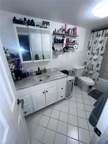 Bathroom featuring vanity, toilet, tile patterned flooring, a textured ceiling, and tile walls