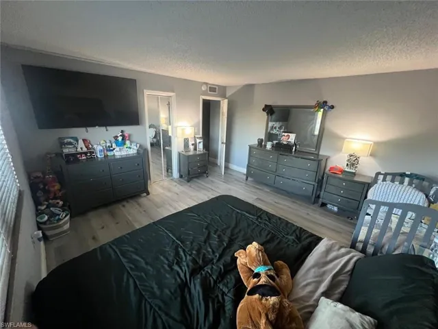 Bedroom with a textured ceiling, wood finished floors, and baseboards