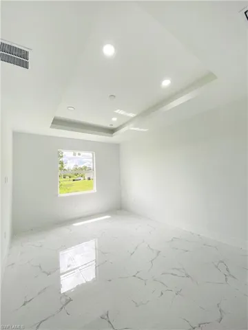Unfurnished room featuring tile patterned flooring and a tray ceiling