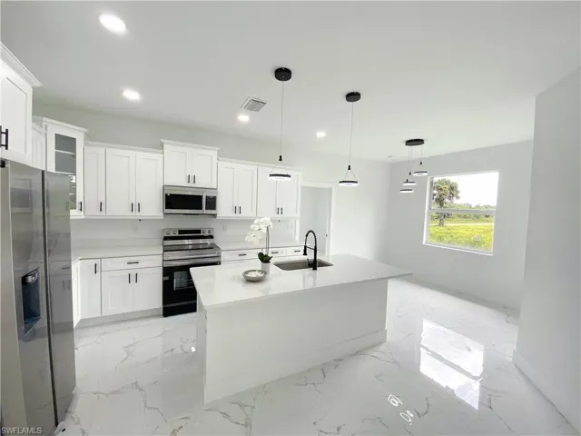 Kitchen featuring white cabinetry, light tile patterned floors, sink, a center island, and stainless steel appliances