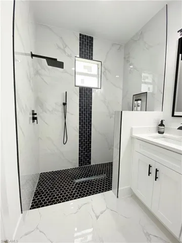 Bathroom with a tile shower, vanity, and tile patterned floors