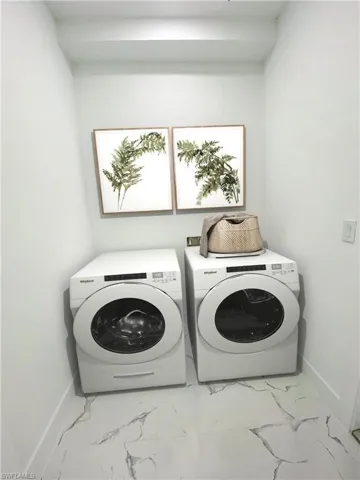 Virtually staged Laundry room featuring washing machine and dryer and light tile patterned floors