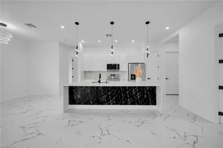 Kitchen featuring stainless steel appliances, modern cabinets, white cabinetry, recessed lighting, and light countertops