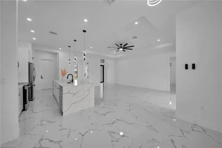 Unfurnished living room featuring recessed lighting, light marble finish flooring, ceiling fan, and a raised ceiling