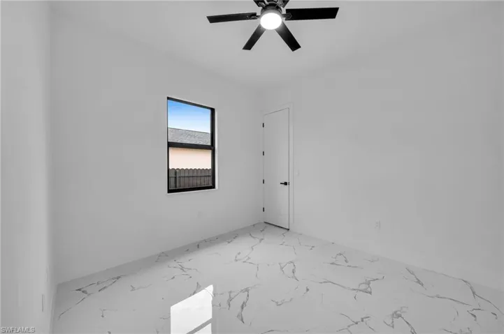 Spare room featuring light marble finish flooring and a ceiling fan