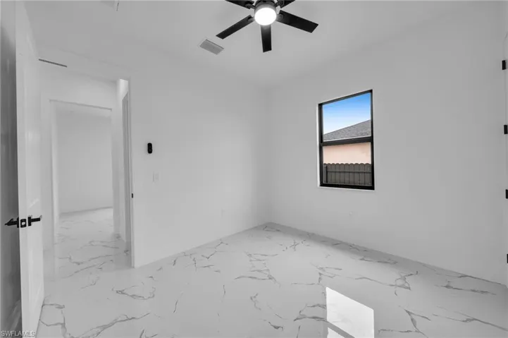 Spare room featuring marble finish flooring and a ceiling fan