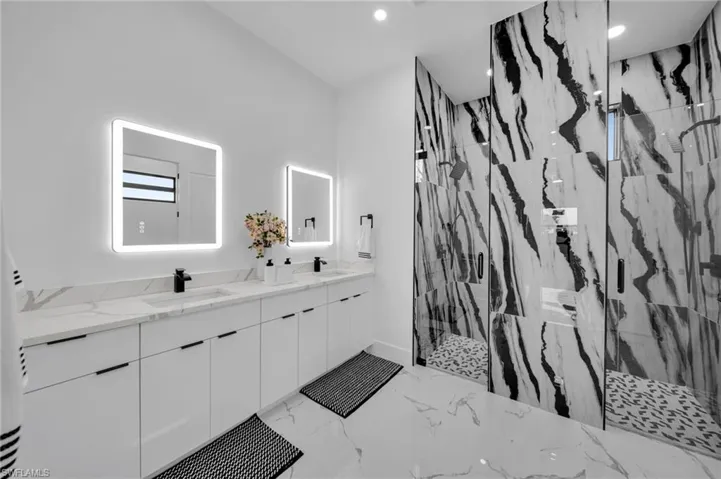 Bathroom featuring double vanity, a marble finish shower, recessed lighting, and marble tiled flooring