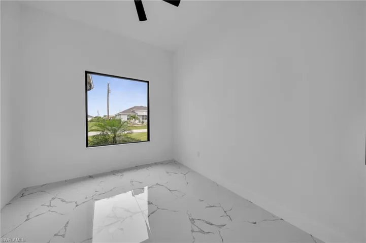 Unfurnished room with marble finish floors and a ceiling fan