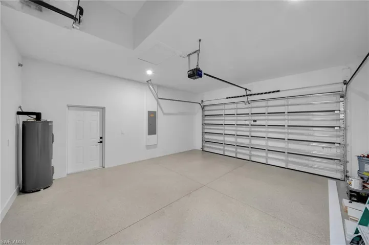 Garage with a garage door opener, electric panel, and water heater
