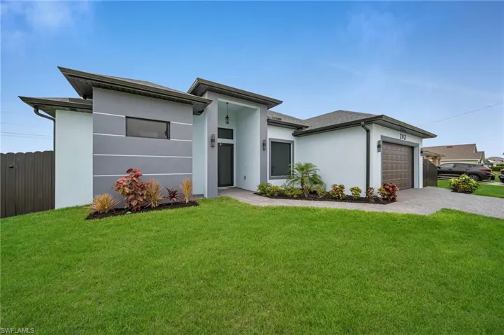 View of front of house with stucco siding, decorative driveway, and an attached garage
