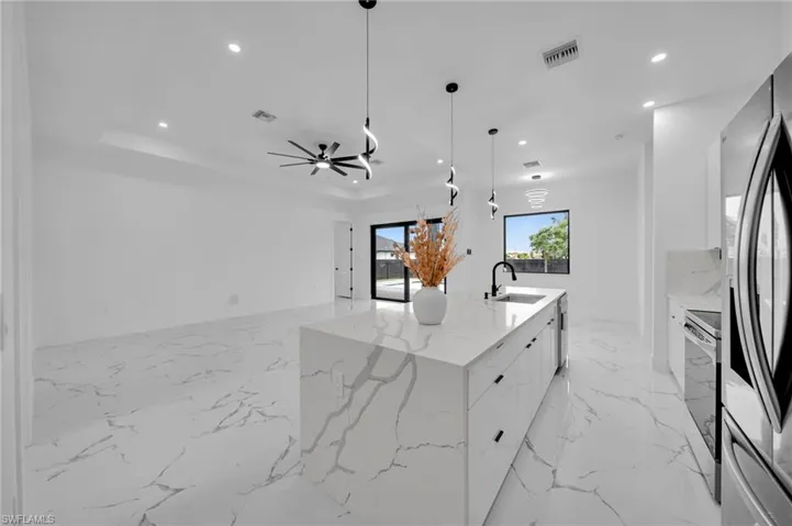 Kitchen with modern cabinets, recessed lighting, white cabinets, light marble finish floors, and a ceiling fan