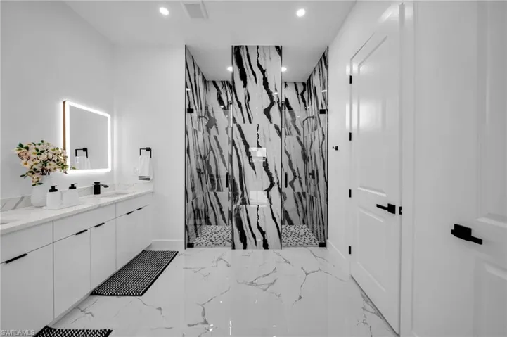 Full bath with a marble finish shower, double vanity, recessed lighting, and marble finish floors