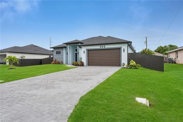 View of front of property with stucco siding, decorative driveway, a garage, and roof with shingles