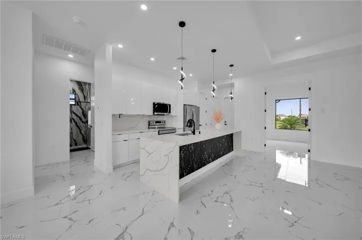 Kitchen featuring modern cabinets, appliances with stainless steel finishes, recessed lighting, white cabinets, and light marble finish flooring