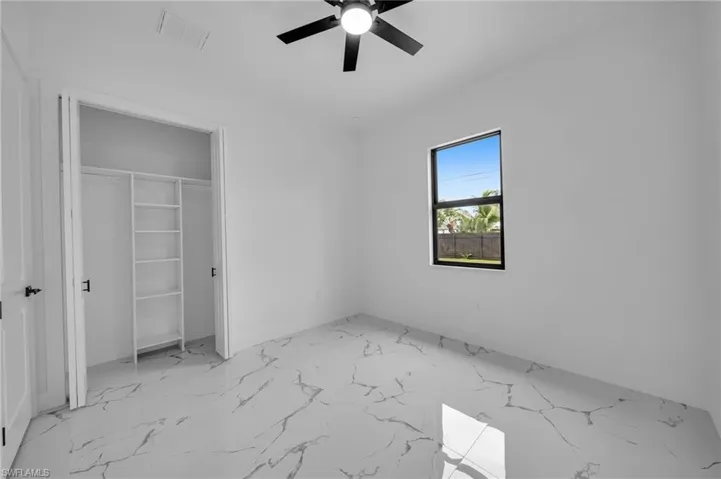 Unfurnished bedroom featuring marble finish floors, a closet, and ceiling fan