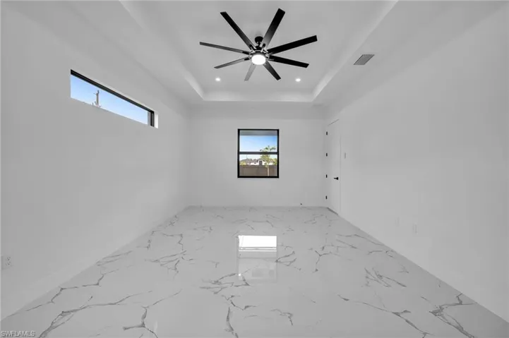 Empty room featuring recessed lighting, marble finish flooring, a raised ceiling, and ceiling fan