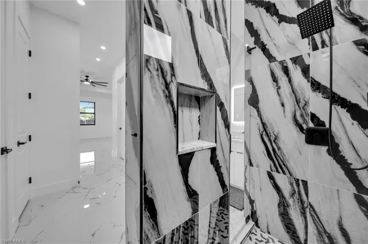 Bathroom view of recessed lighting, a marble finish shower, and a ceiling fan
