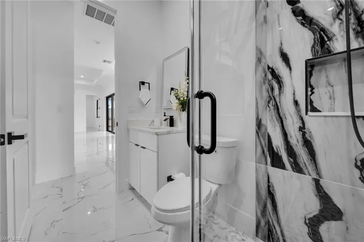 Full bathroom featuring vanity, marble tiled floors, and a marble finish shower
