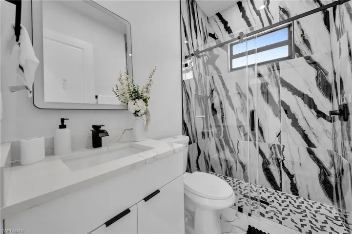 Full bath with vanity, a marble finish shower, and marble finish flooring