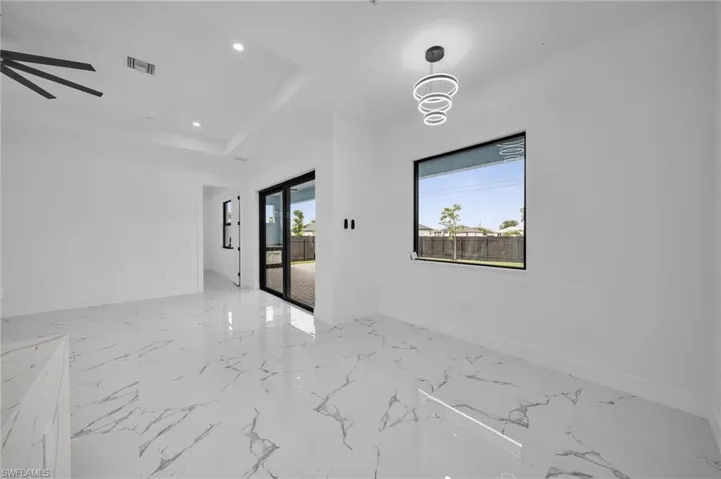 Empty room featuring light marble finish flooring, ceiling fan, recessed lighting, and a tray ceiling