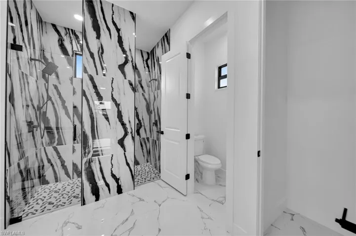 Full bath with a marble finish shower and marble finish floors