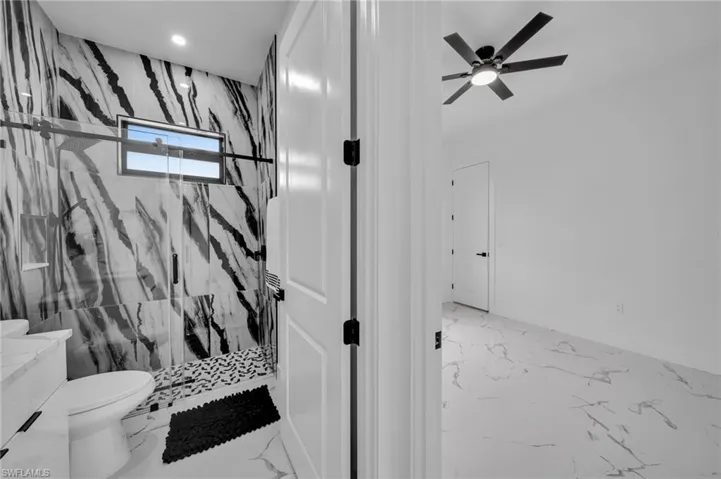 Full bathroom featuring marble tiled flooring, a marble finish shower, a ceiling fan, recessed lighting, and vanity