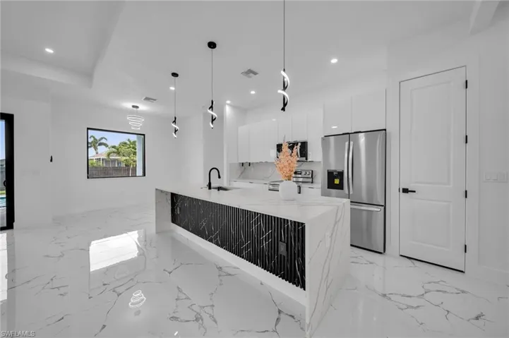 Kitchen with stainless steel appliances, modern cabinets, white cabinetry, recessed lighting, and light marble finish flooring