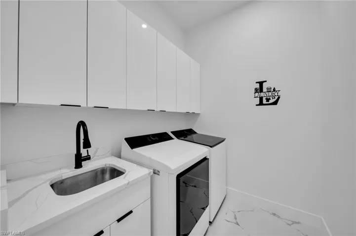 Washroom with washer and dryer, marble look tile flooring, and cabinet space