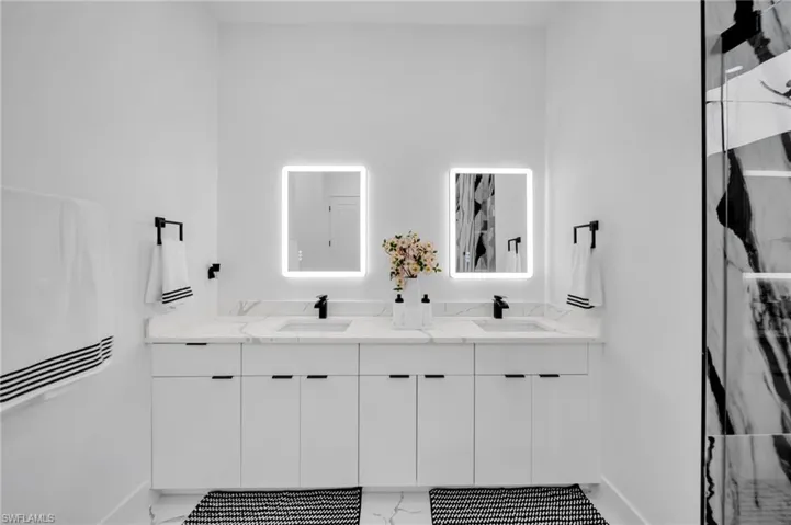 Full bathroom with marble look tile flooring, double vanity, and a marble finish shower