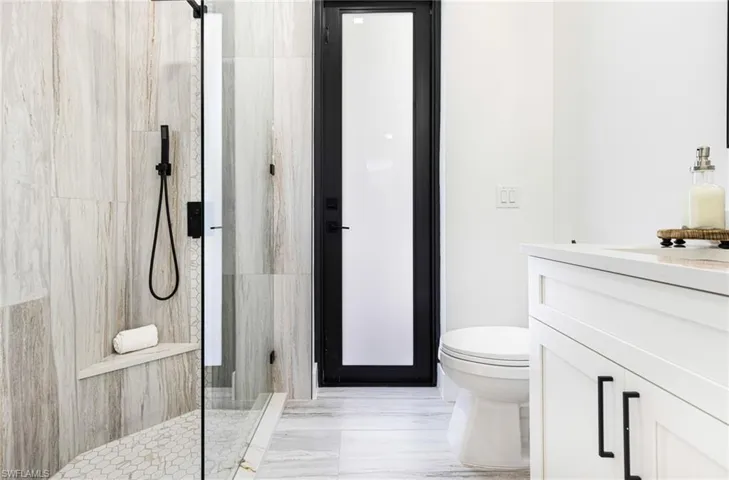 Pool Bathroom with upgraded tile and custom niche and bench. Glass shower doors.