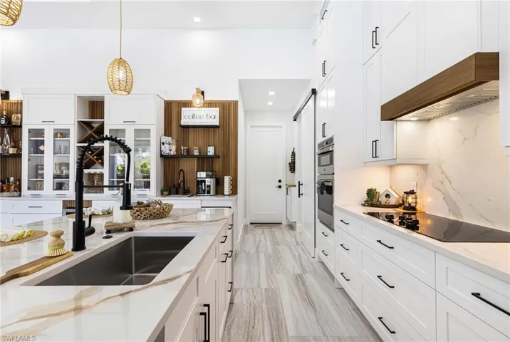 Kitchen featuring upgraded Quartz counter tops, electric cooktop, and white shaker cabinets custom with glass and pop open hinges.
