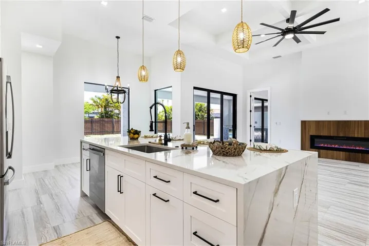 Large custom Kitchen  island with sink, decorative light fixtures, and waterfall quartz tops. Seating for 6.