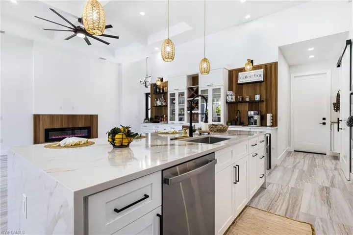 Kitchen featuring dishwasher, a center island with sink, ceiling fan, and custom features.