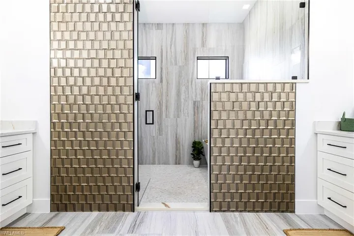 Large Primary bathroom with custom upgraded beveled glass tile and glass shower door.